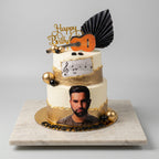 gâteau deux étages kendji girac , doré et couleur vanille , il  la photo du chanteur en vas puis a letage a droite deux boule une doré et une noir au milieu des note de musique , au dessus  boule deux doré et une noir , une guitare le chiffre  et écrit en doré happy birthday 